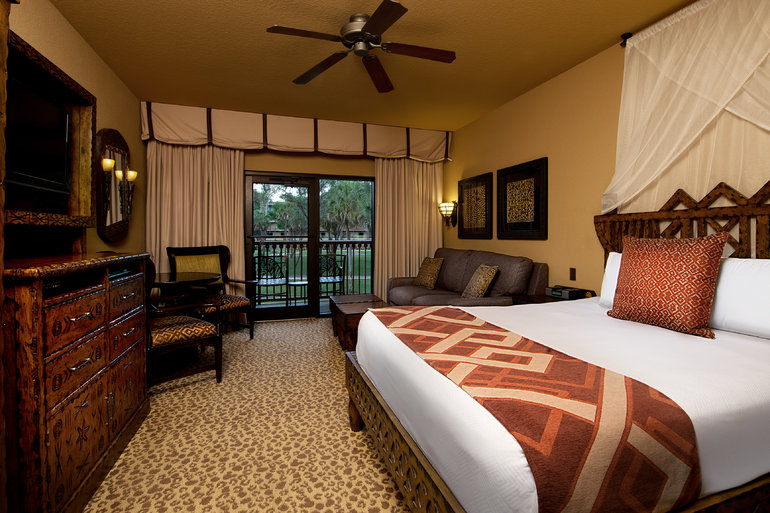 Image shows an african inspired room  with a double bed, fan and patio door