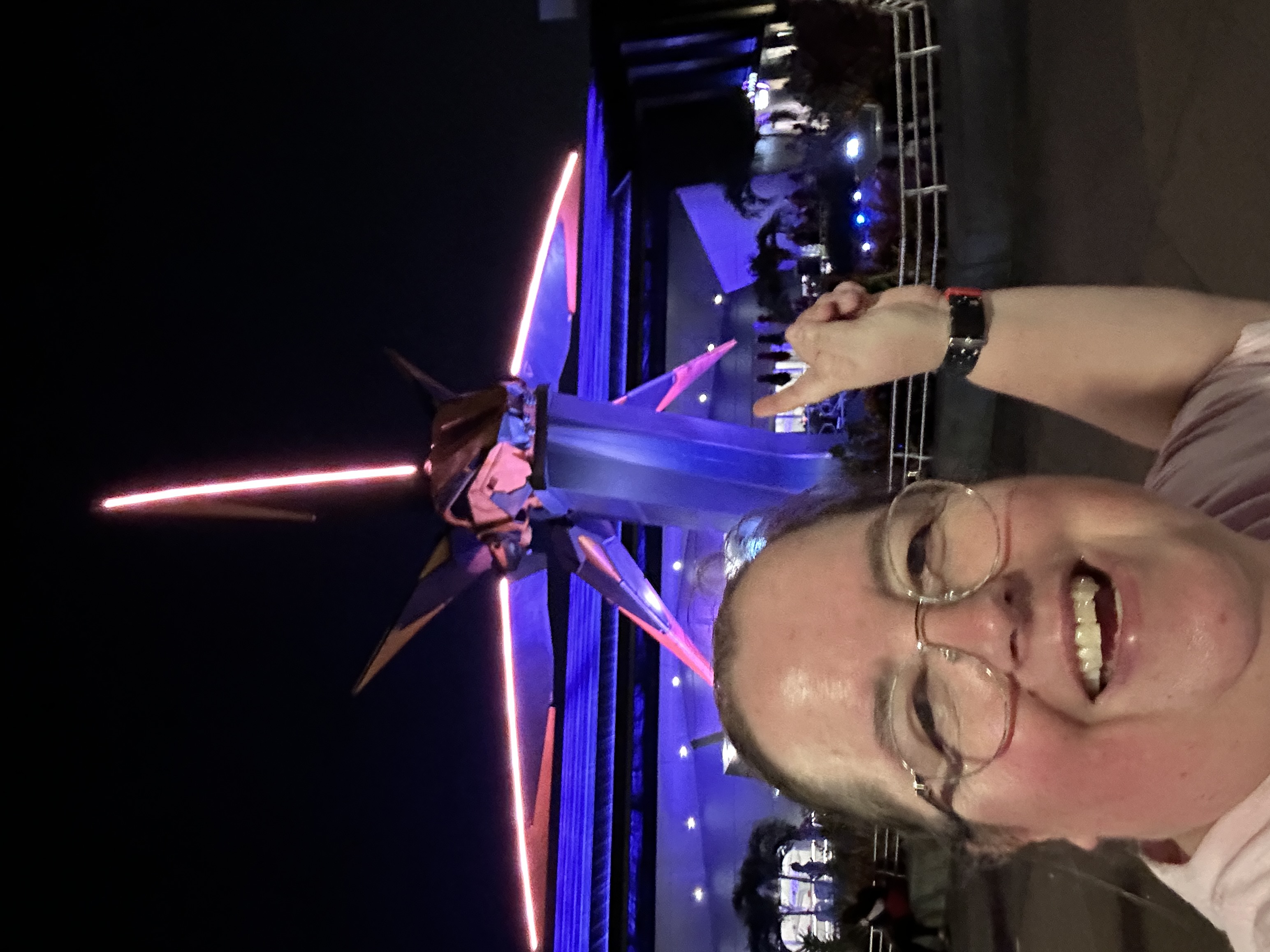 a lady pointing to a star shape ship illuminated in neon lights