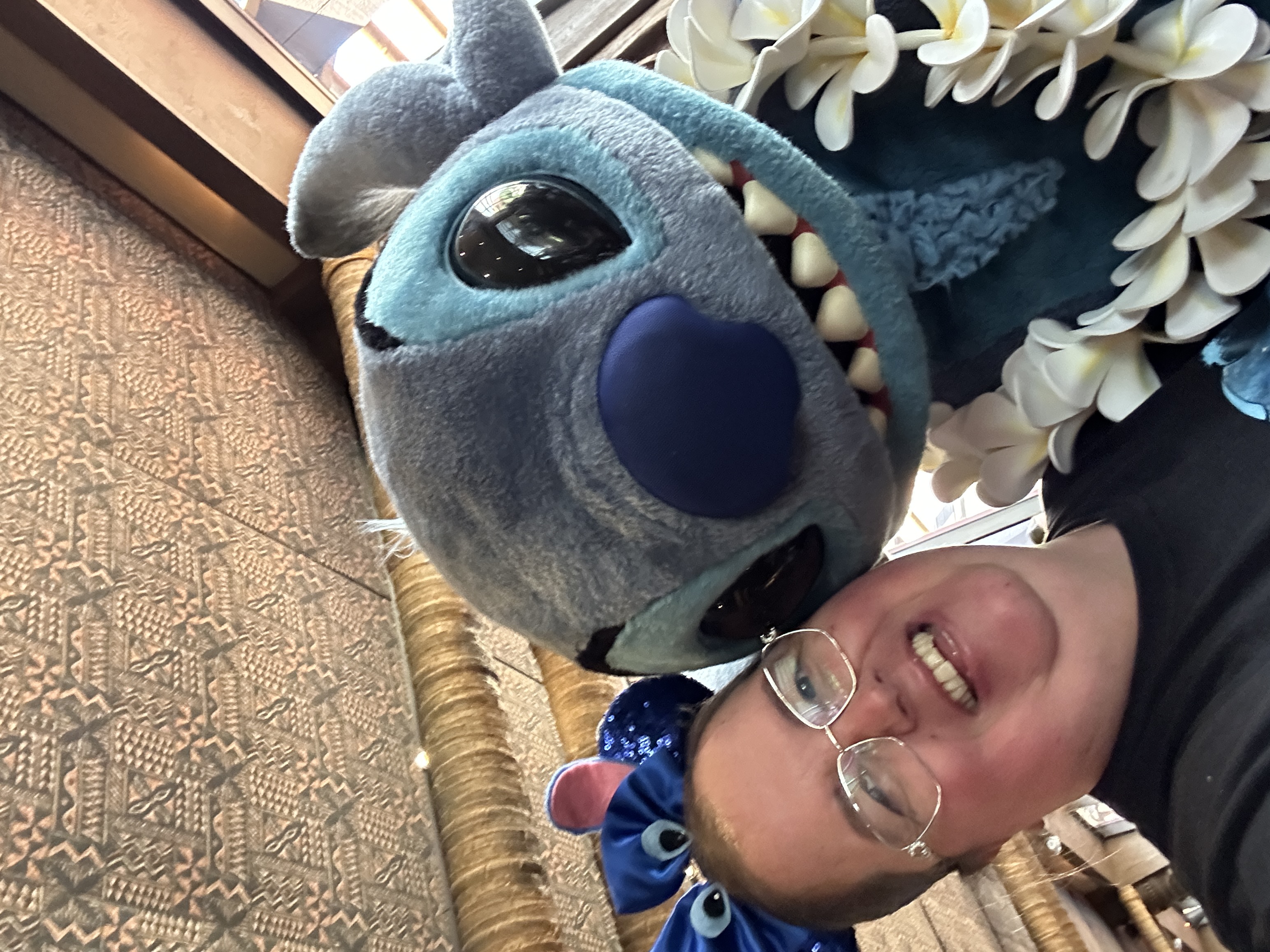 Image is a lady with a ear headband on smiline next to a blue character called Stitch