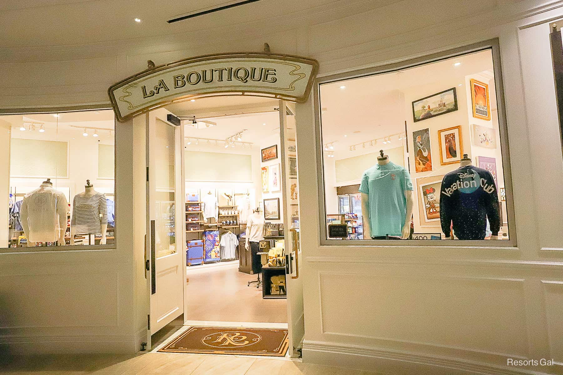 Image shows a shop front with two windows both with some clothing as displays with the words La Boutique over the door
