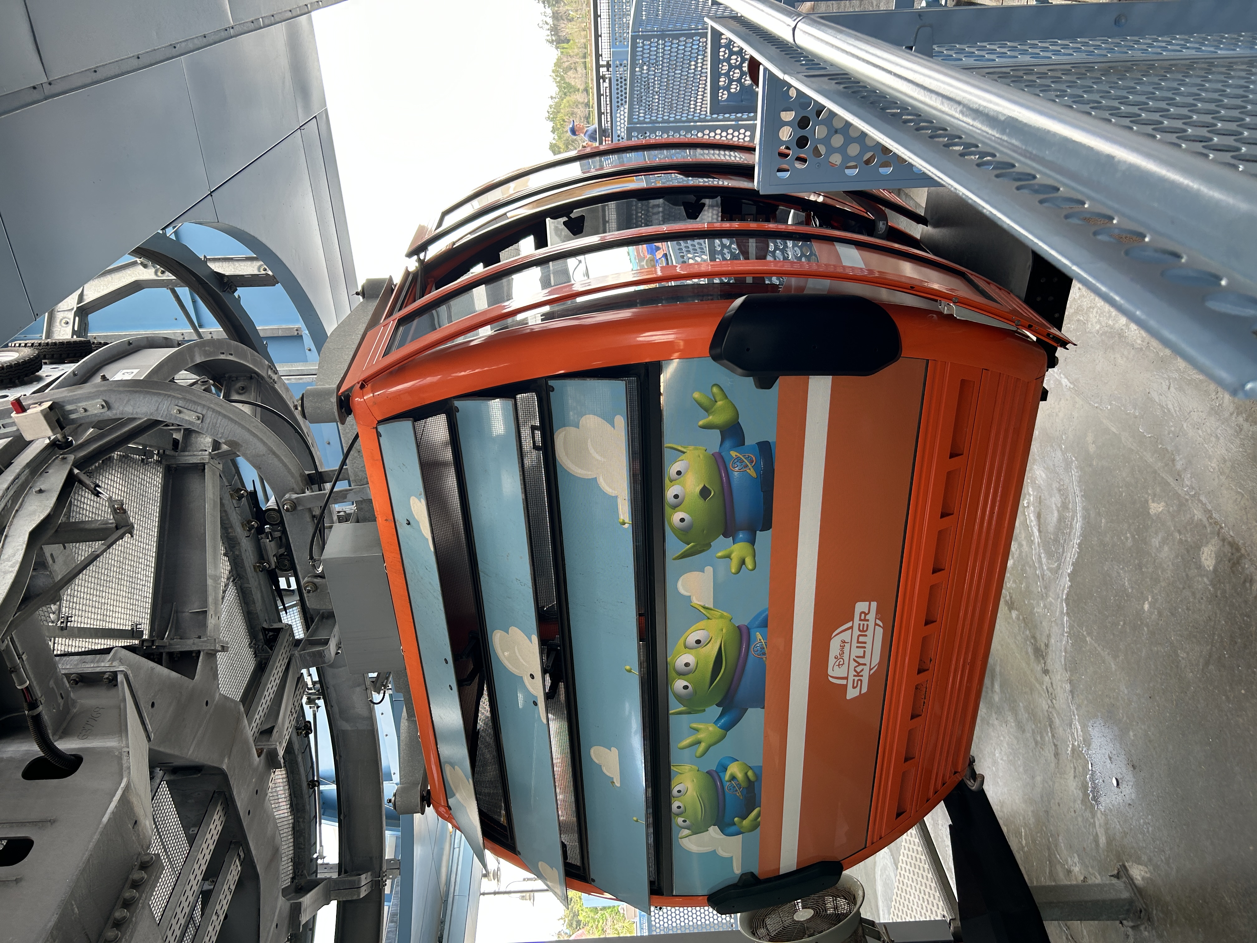 image shows a red cable car with green fun aliens on