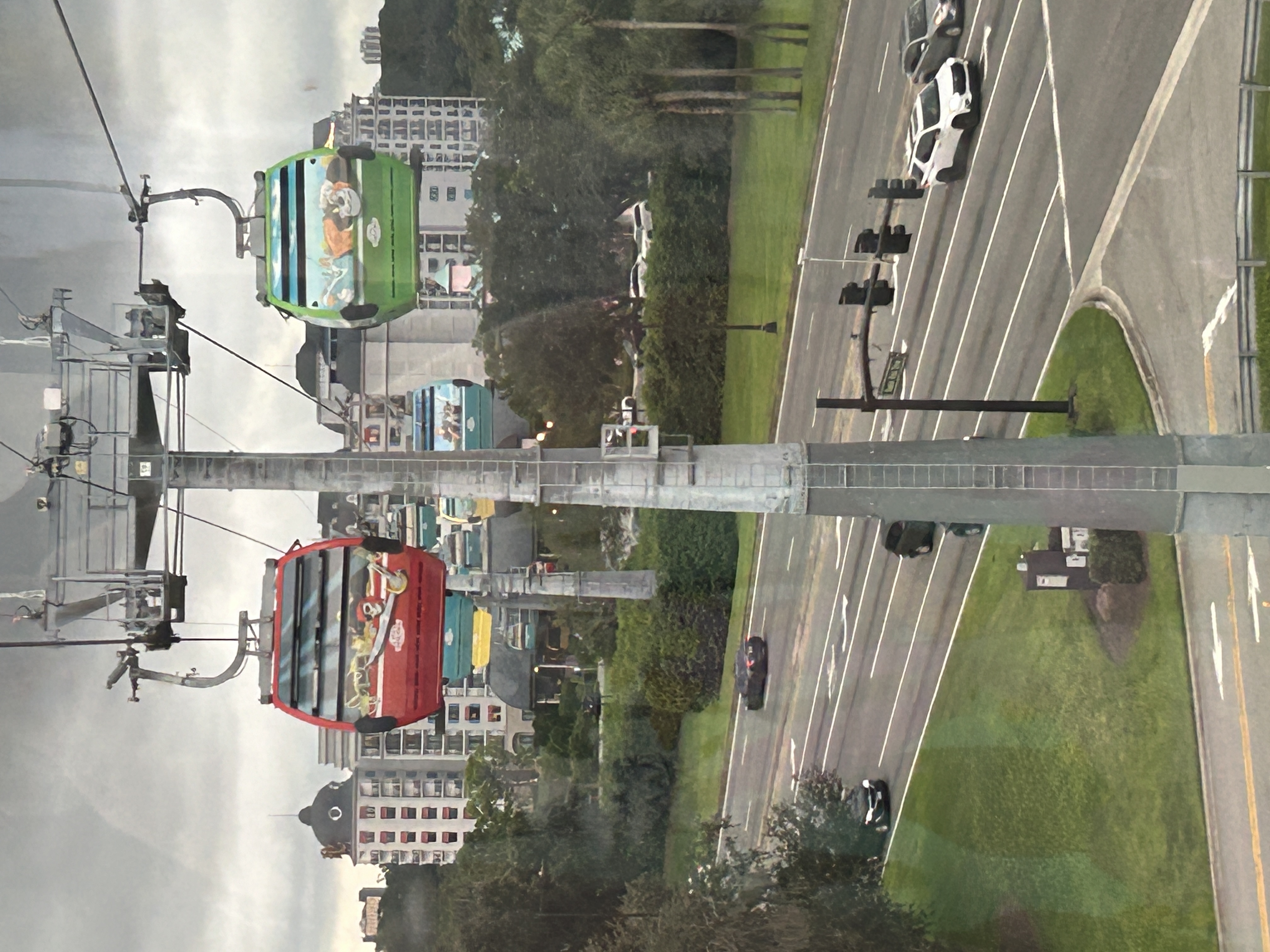 Inmage shows a view over trees with two cable cars hanging from a wire