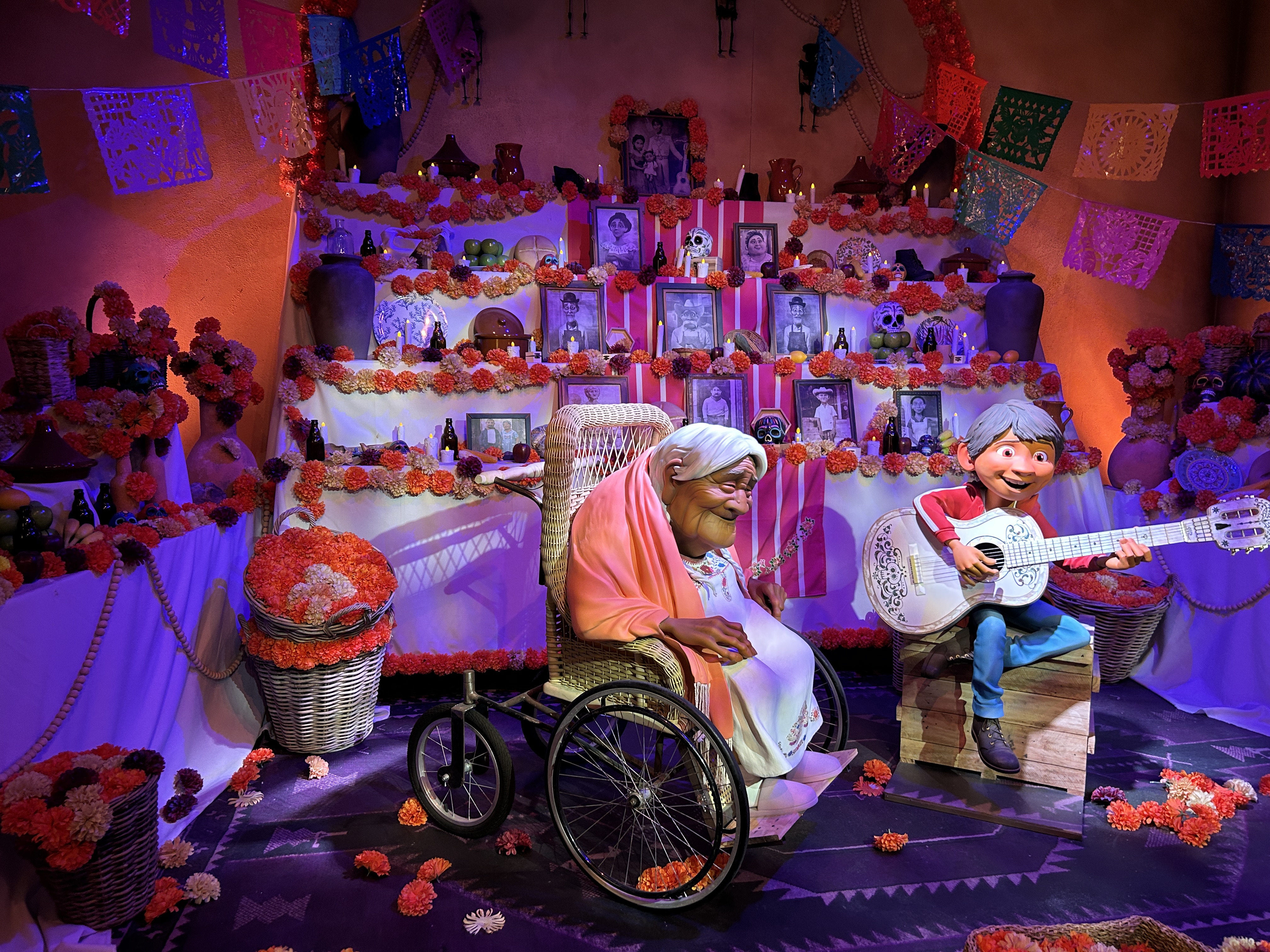 A traditional Mexican ofrenda, with an old lady in a wheelchair and a child playing a white guitar