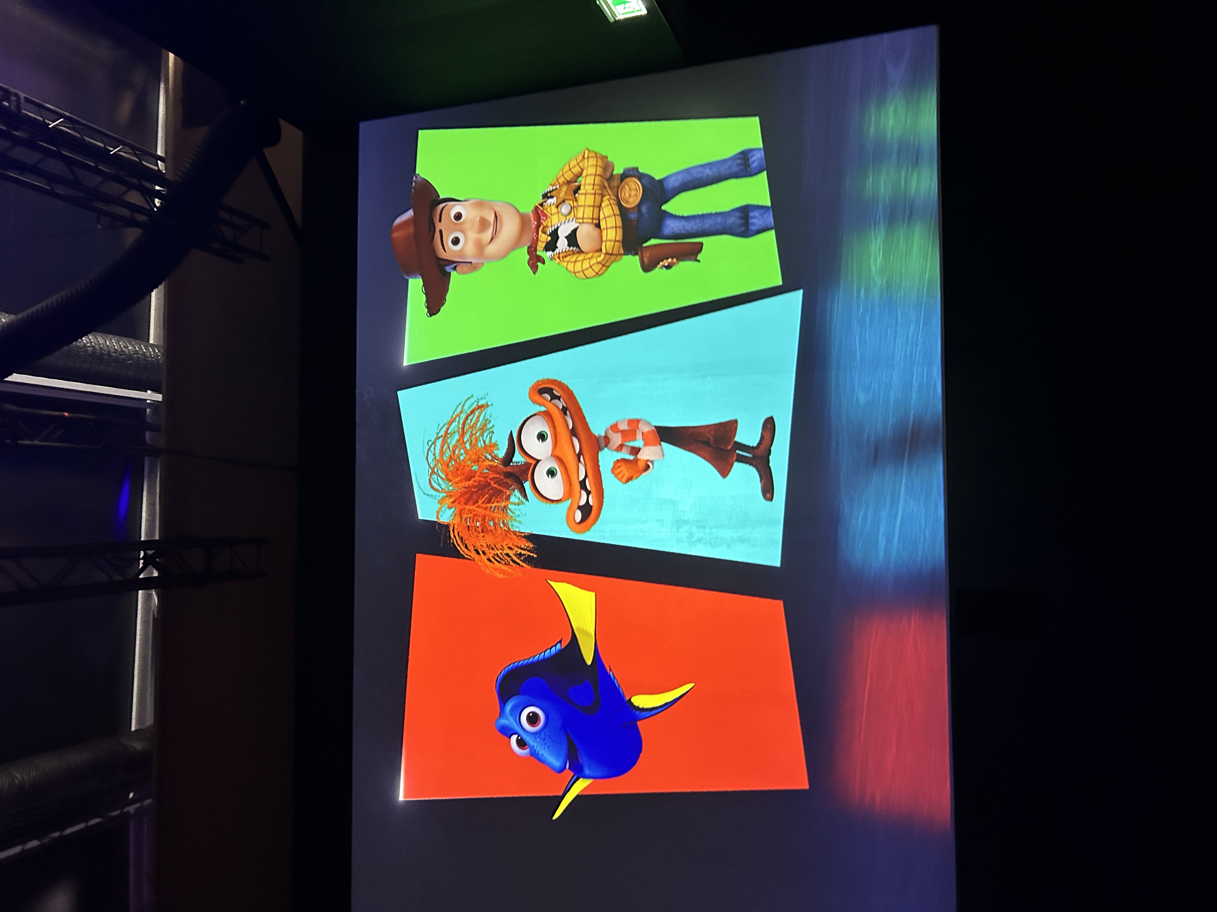 Three coloured film backdrops on a screen: red with a blue-and-yellow fish, blue with an orange-haired character, and green with a cowboy toy
