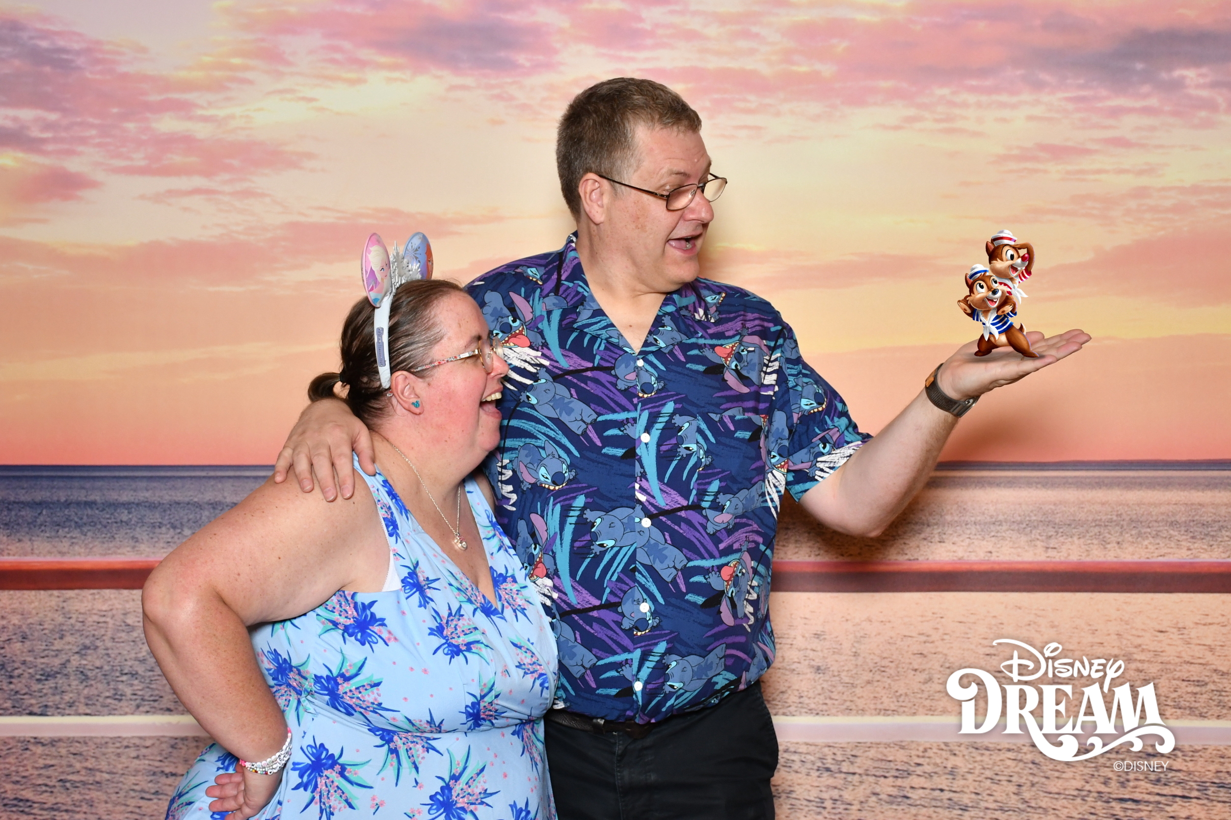 Image shows a man in a blue Hawaiian shirt and a lady in a blue dress looking surprised at the man's hand, which is holding two cartoon chipmunks