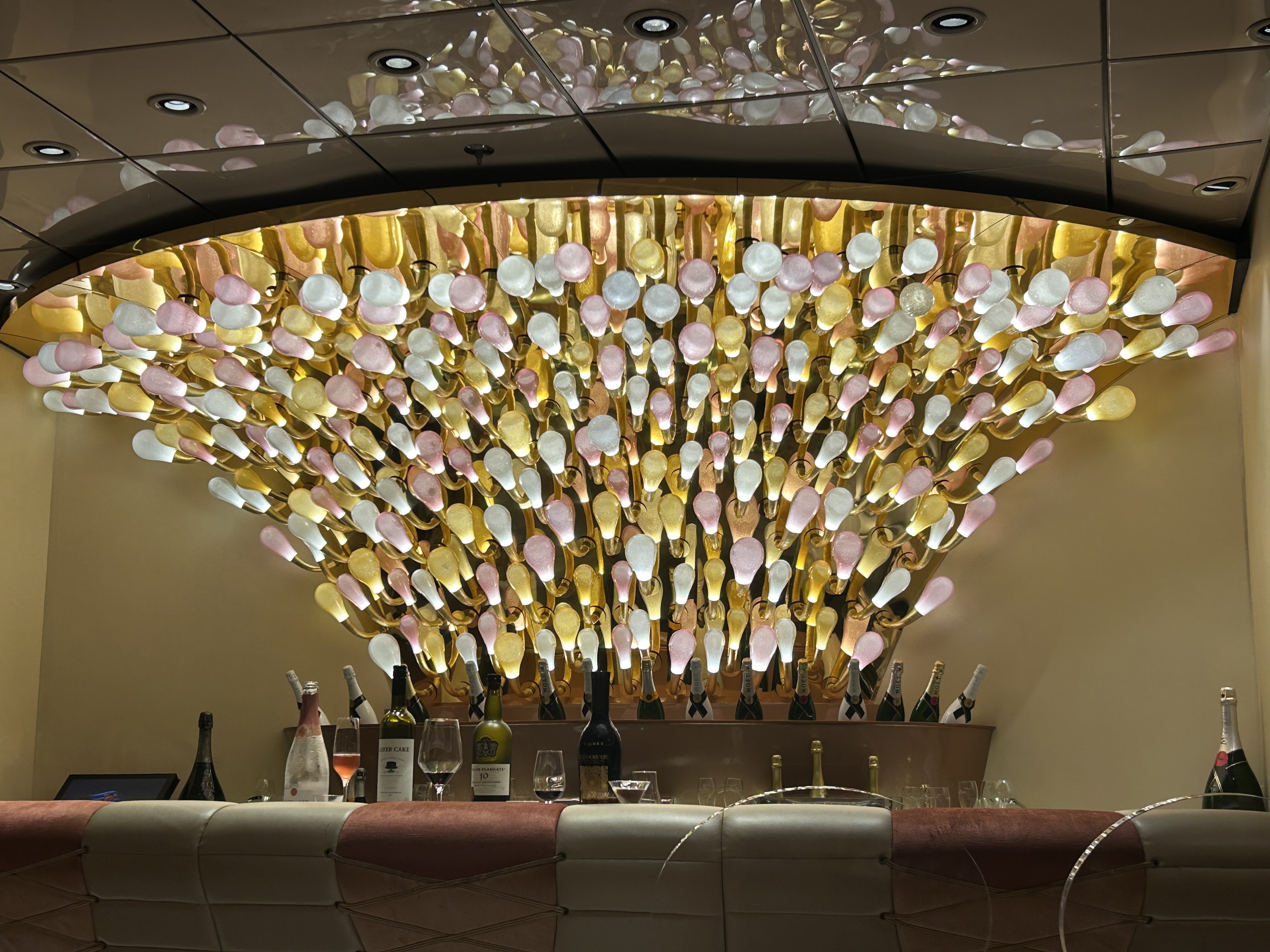 Image shows Pink, the champagne bar on the Disney Dream, with glass-ball lighting above and bottles behind the bar