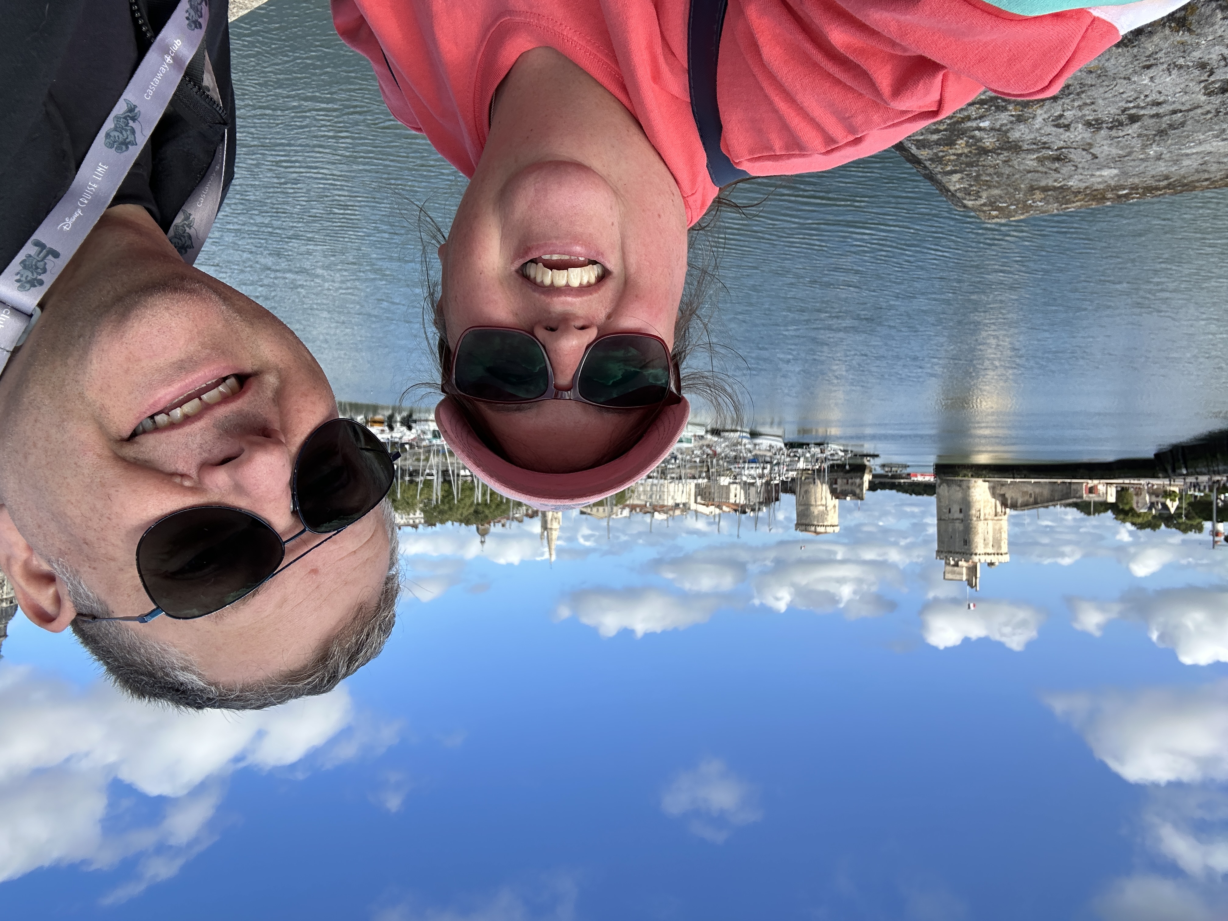 Image shows a man and woman standing in front of the harbour at La Rochelle