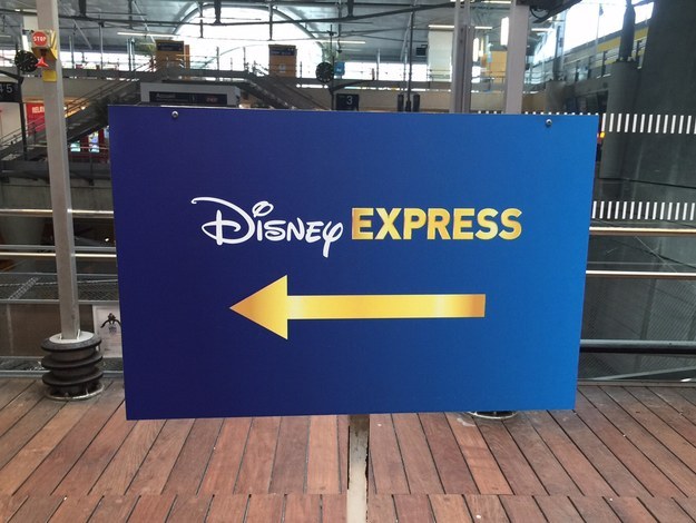 Image is a blue rectangle sign with  a gold arrow pointing left and the words Disney Express on